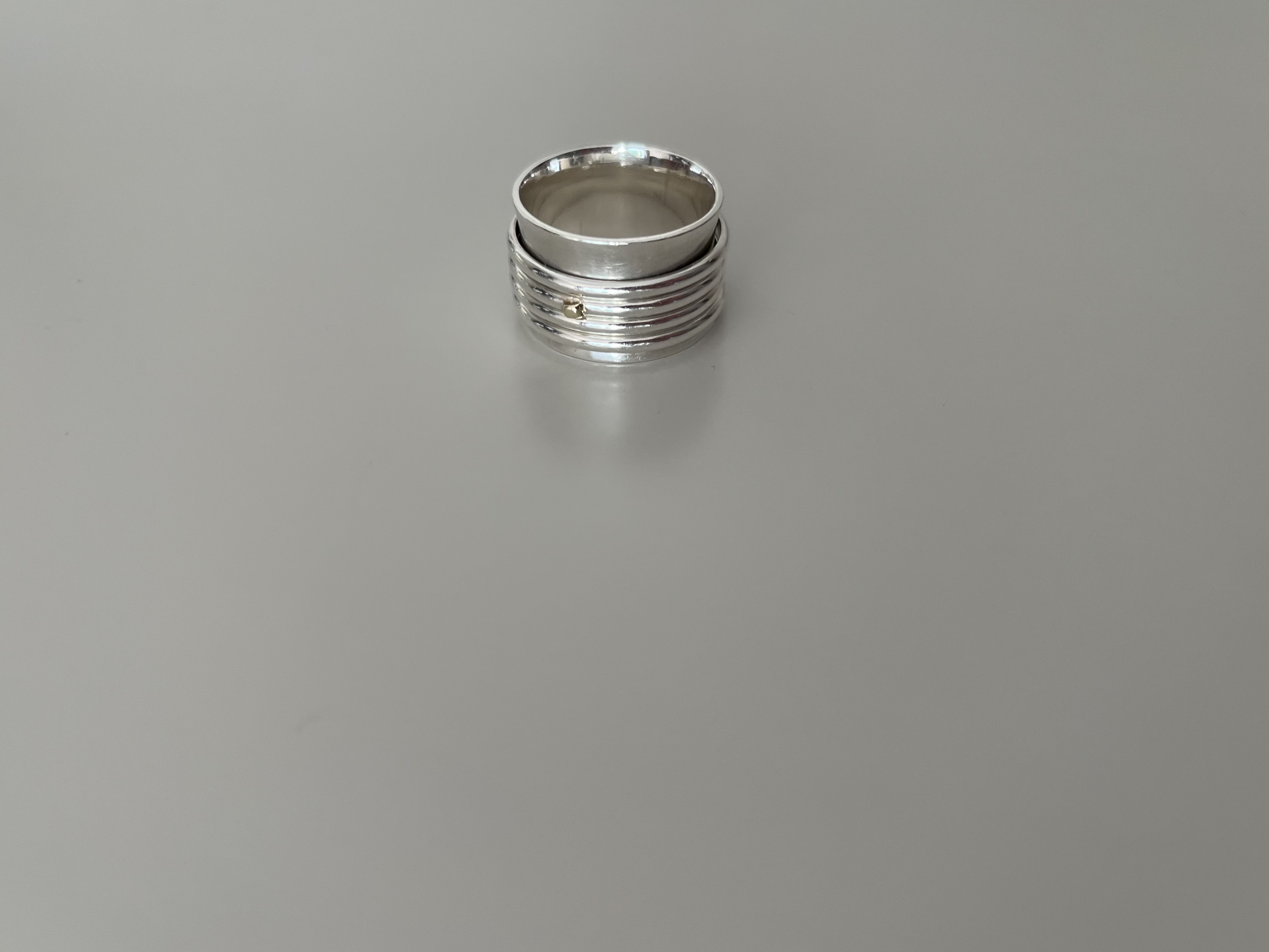Stack of wide silver rings with a tiny gold accent