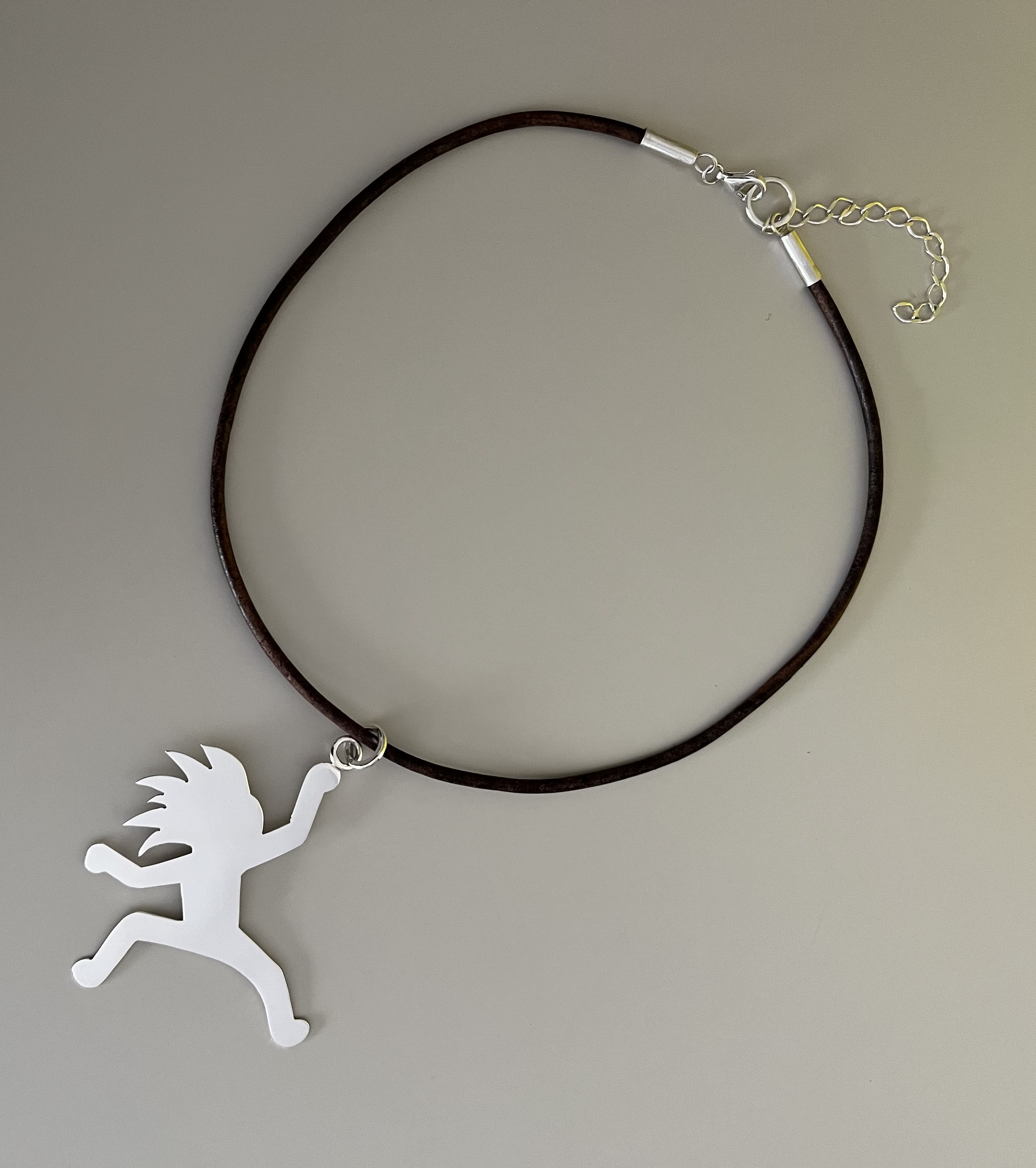 Large playful running-figure charm on a dark cord necklace
