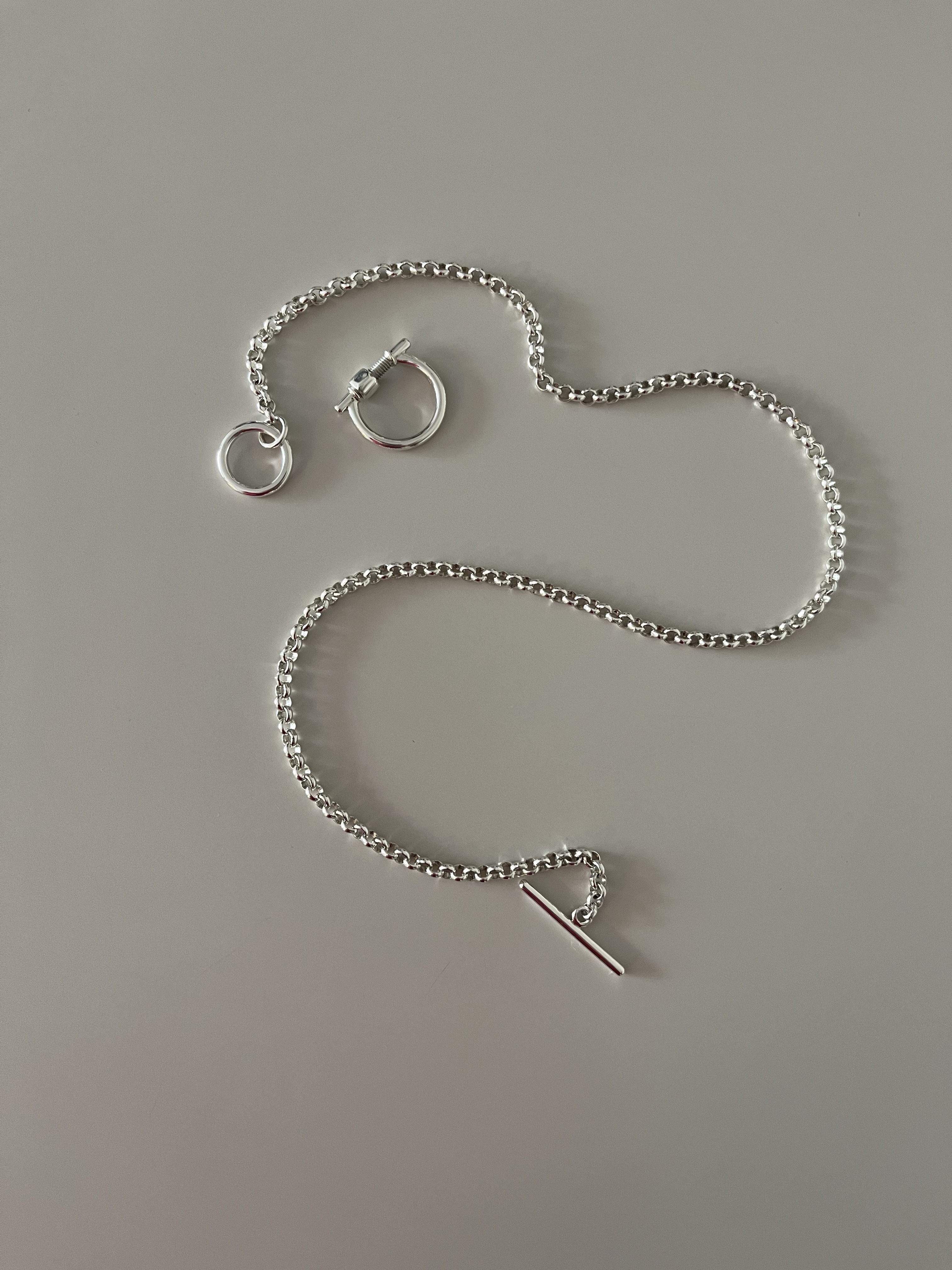 Silver Omega lock with chain and toggle clasp on a neutral surface