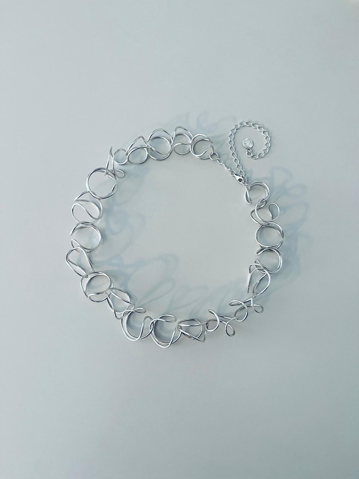Handmade silver wire necklace on a light background